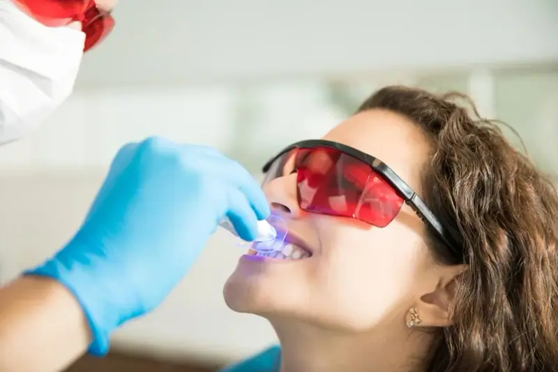 بیمار در حال دریافت سفید کردن حرفه‌ای دندان با نور UV در Texas Dental Center.